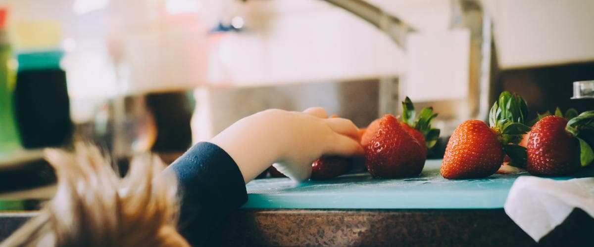 Child reaching out for strawberries.